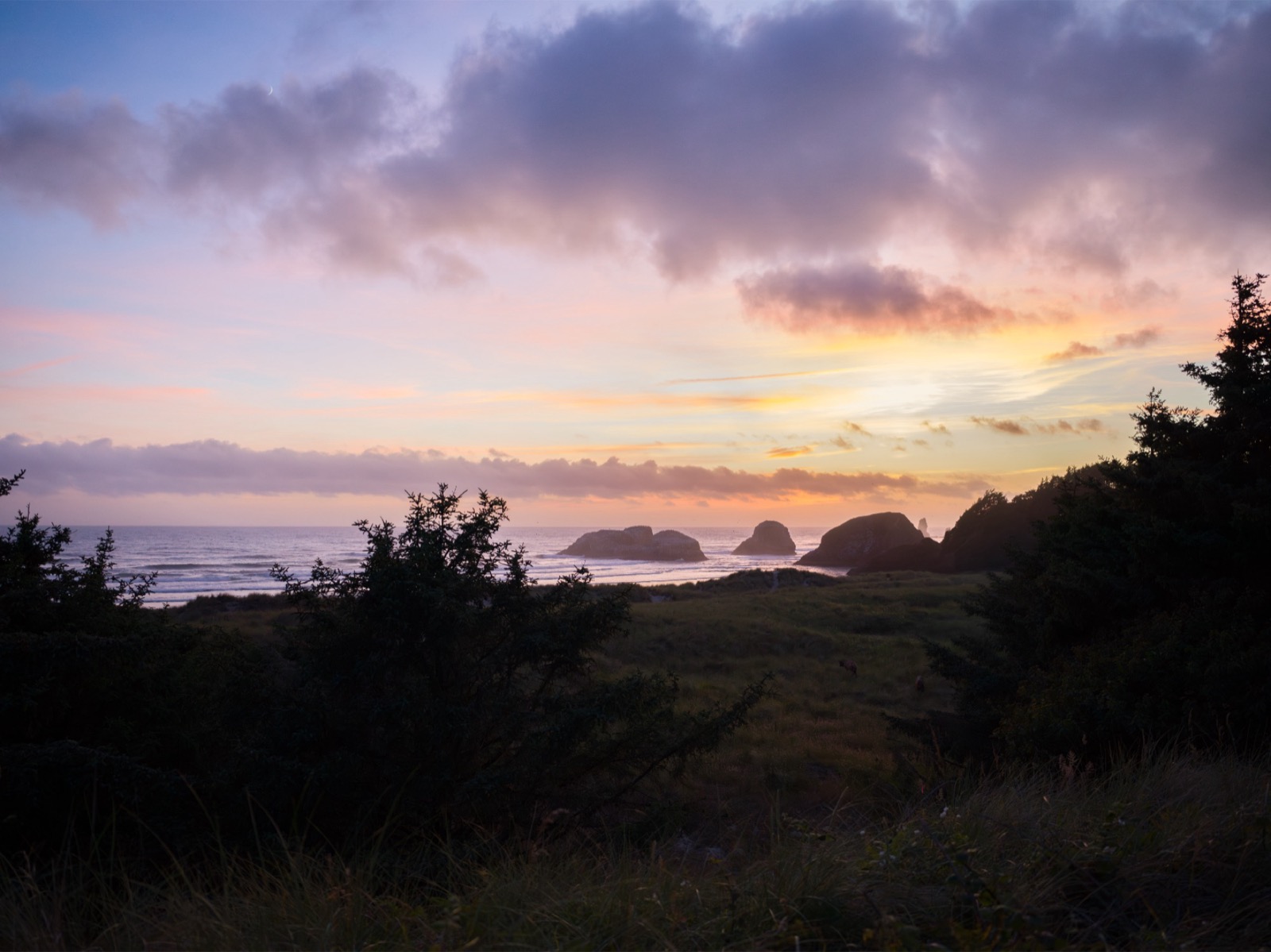 Ocean breaking over rocks at Cannon Beach at dusk